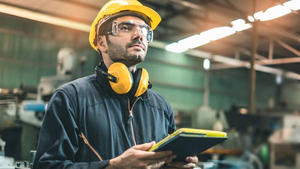 مهندس صنعتی با کلاه های سخت در کارخانه تولید صنایع سنگین کار می کنند